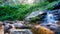 Crystal clear water that falls between large rocks in an enchanted forest of the Sierra de Guadarrama, Madrid.