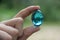 Crystal glass ball in human hand on defocused grass background. Saving environment, save clean green planet, ecology concept