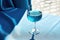 Crystal glass with blue wine placed on a table draped with blue fabric. Natural Sunny summer light and delicate shadows create an