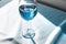 Crystal glass with blue wine placed on a table draped with light blue fabric. Natural Sunny summer light and delicate shadows