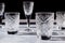 Crystal glasses on textured table with hard light and long clear shadow. Sun glare, light refraction on transparent faceted dishes