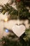 Crystal heart Christmas tree ornament on green branch with string lights and copy space. Winter love card