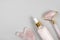 Crystal rose quartz facial roller, massage tool Gua sha and anti-aging collagen, serum in glass bottle on grey background. Facial