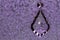 Crystal Teardrop Pendant, Hanging Against Lavender Background.