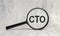 CTO abbreviation and magnifier on wooden background