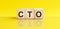 CTO - Chief technical officer - word is made of wooden building blocks lying on the yellow table