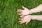 Cuacasian female hands with palms up on green grass, close-up view