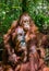 Cub of orangutan on mother`s back in green rainforest.