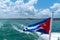 Cuba flag waving on boat at sea near Cuban coastline