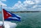 Cuba flag waving on boat at sea near Cuban coastline