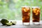 Cuba Libre cocktail with lime, ice, mint and rum on wooden table with a view to the terrace. Copy space for text