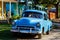 Cuban car parked in front of tropical home in rural Cuba