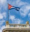 Cuban flag of red, white and blue, flies on top of building in Havana