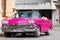 Cuban man on his american pink 1958 Chevrolet classic car convertible in the old town from