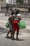 Cuban women standing by road, carrying green bags in Havana