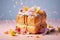 A cube-shaped croissant covered with multi-colored icing and sprinkled with flowers.