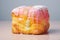 A cube-shaped croissant covered with multi-colored icing and sprinkled with flowers.