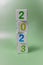 Cube tower with colorful numbers 2023 in center of the photo on green background. New year, calendar.