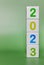 Cube tower with colorful numbers 2023 on green background with copy space. New year, calendar.