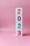 Cube tower with colorful numbers 2023 on pink background with copy space. New year, calendar.