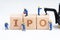 Cube wooden block with alphabets combine the word IPO with miniature people men help building with crane on white background using
