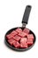 Cubes of raw beef meat on small frying pan isolated on white