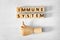 Cubes with words Immune System and mannequin hand showing thumb up gesture on white wooden table, flat lay