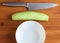 Cucumber, plate and knife on a cutting board.