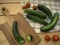 Cucumber sliced on a cutting board and other on a kitchen towel and cherri tomatoes