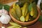 Cucumbers in a wooden bowl, spices for pickling and jars of pickled cucumbers on the table