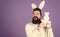 Cuddly bunny. Symbolizing spring, new life and fertility. Bearded man in easter rabbit costume holding hare toy. Happy