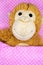 Cuddly toy monkey for children in bed under a pink duvet with white dots for congratulations cards and postcards