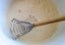 Culinary whisk for whipping with wooden handle in a white bowl with beaten eggs and sugar
