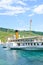 Cully, Switzerland - August 11, 2019: Sightseeing boat with tourists on Lake Geneva. Vineyards on the slopes in background. Lavaux