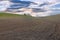 cultivated plowed field at dusk under cloudy sky