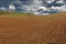 Cultivated plowed field at dusk under cloudy sky