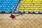 Cultivator stands on the sand in the middle of a sporty small stadium with blue and yellow seats of fans.