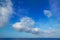Cumulus clouds in blue sky over water horizon