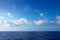 Cumulus clouds in blue sky over water horizon