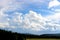 Cumulus clouds over tops of green trees