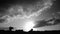 Cumulus in sunset running fast over the countryside. Black and white timelapse footage of cloudscape. Silhouettes of houses, farms