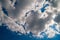 Cumulus white clouds cover the sun. Contrasting clouds on a dark blue windy sky. Natural sky background