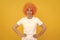 cunning funny girl with fancy look wearing orange hair wig on yellow background, emotions