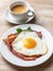 Cup of americano and plate of fried egg with bacon.