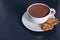 Cup of aromatic cacao with cookies on dark table.