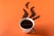 Cup of aromatic coffee and coffee beans on an orange trendy background with space for text