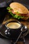 Cup of aromatic coffee and healthy sandwiches with bran bread, cheese, lettuce, tomato and sliced salami and glass of freshly sque