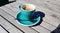 Cup of aromatic coffee in a turquoise cup on a wooden table in the yard