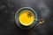 Cup of ayurvedic golden turmeric latte milk with curcuma powder and anise star on black. View from above