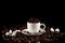 The Cup is on a black background with coffee beans on the table next to the Cup